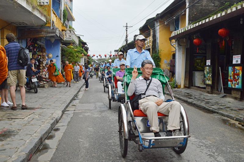 Hình ảnh bãi biển Đà Nẵng thanh bình với người đi dạo, minh họa điểm đến tốt cho tinh thần và sức khỏe khi đi du lịch.