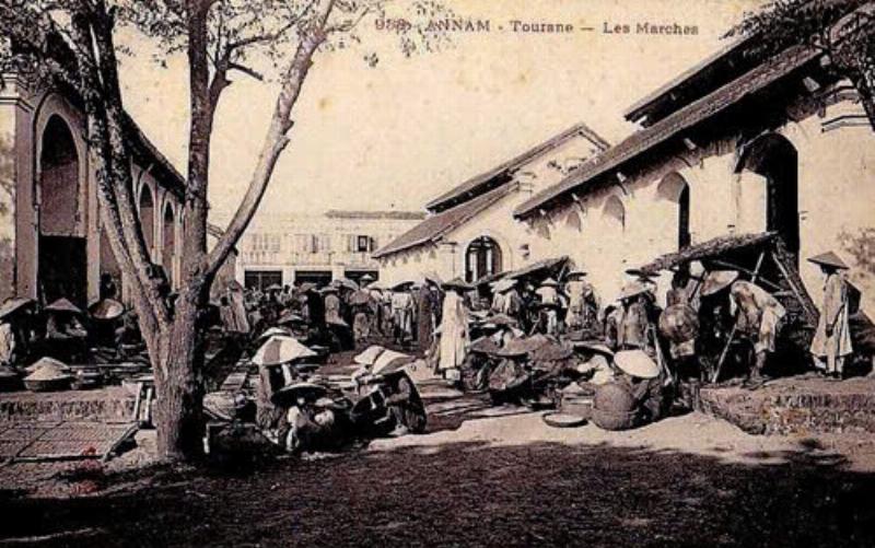 Một con phố nhỏ yên bình gần một trường tiểu học ở Miền Trung, có thể thấy vài cửa hàng nhỏ, quán ăn địa phương, hoặc người dân đi lại nhẹ nhàng, thể hiện không khí đời sống thường nhật.